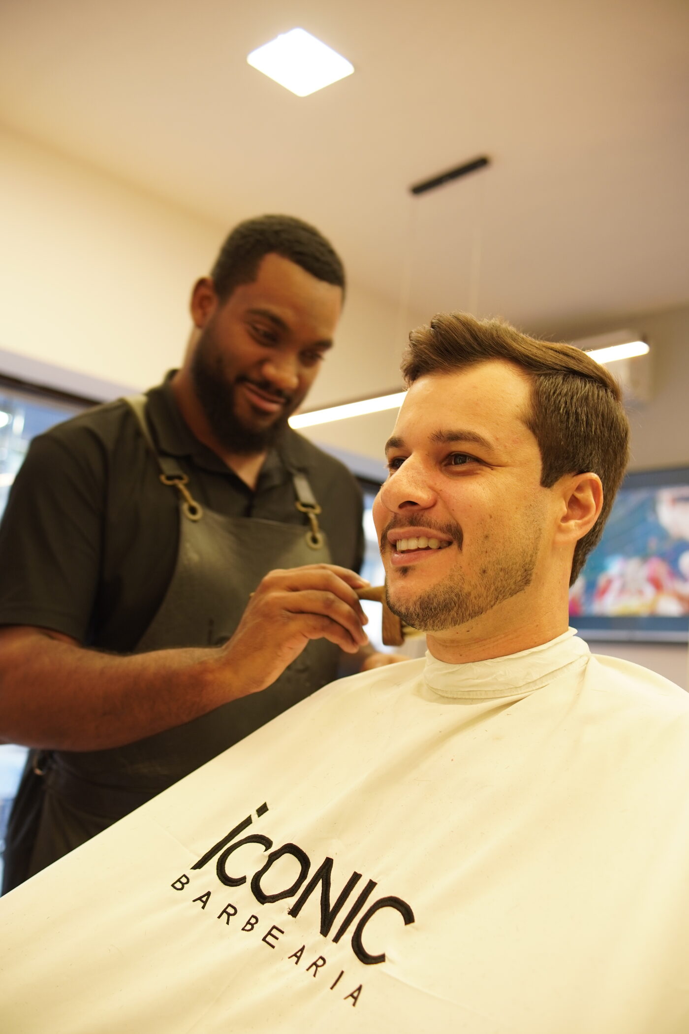 Barbeiro finalizando barba de cliente com pincel