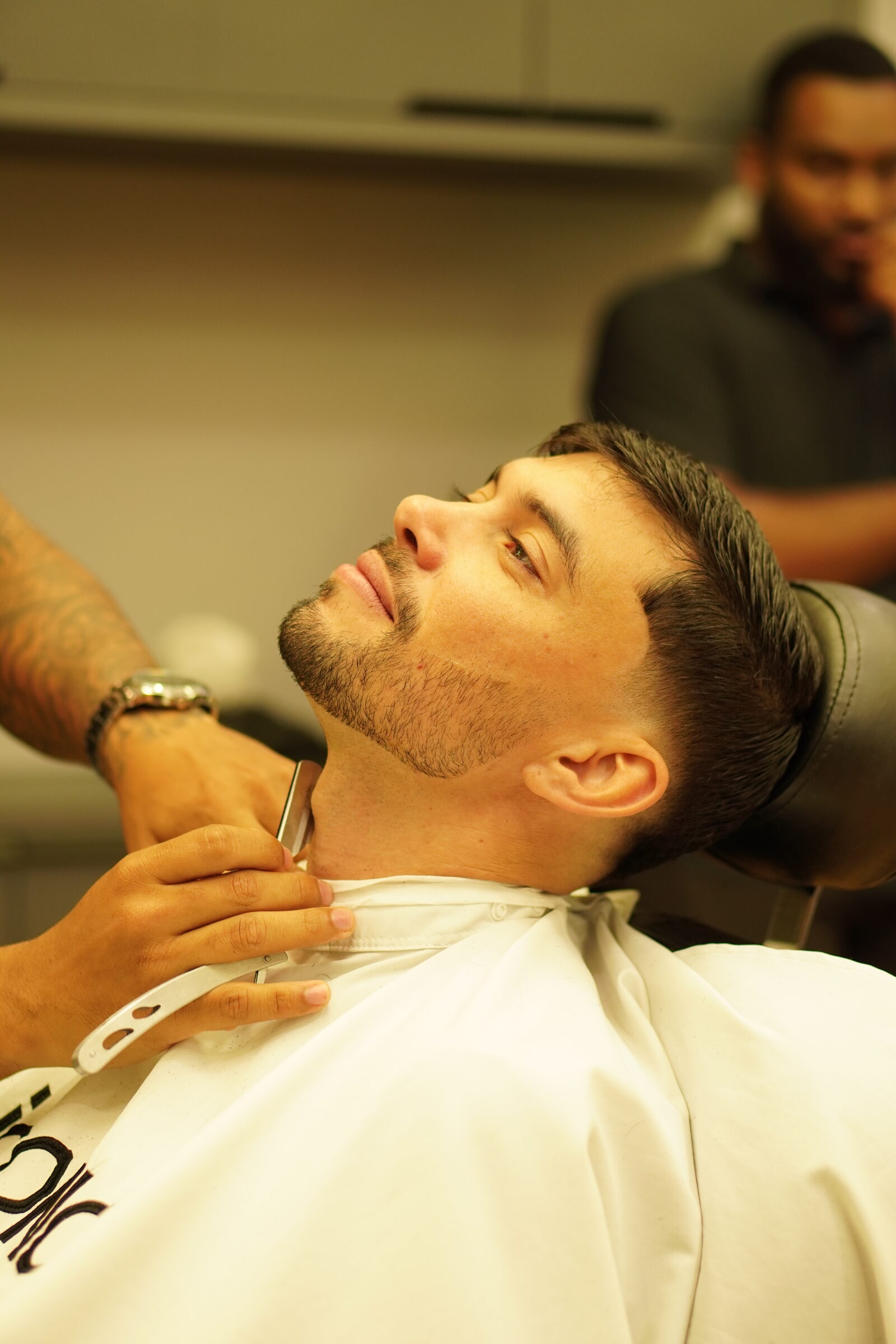 Barbeiro da Iconic Barbearia finalizando a barba de um cliente com navalha