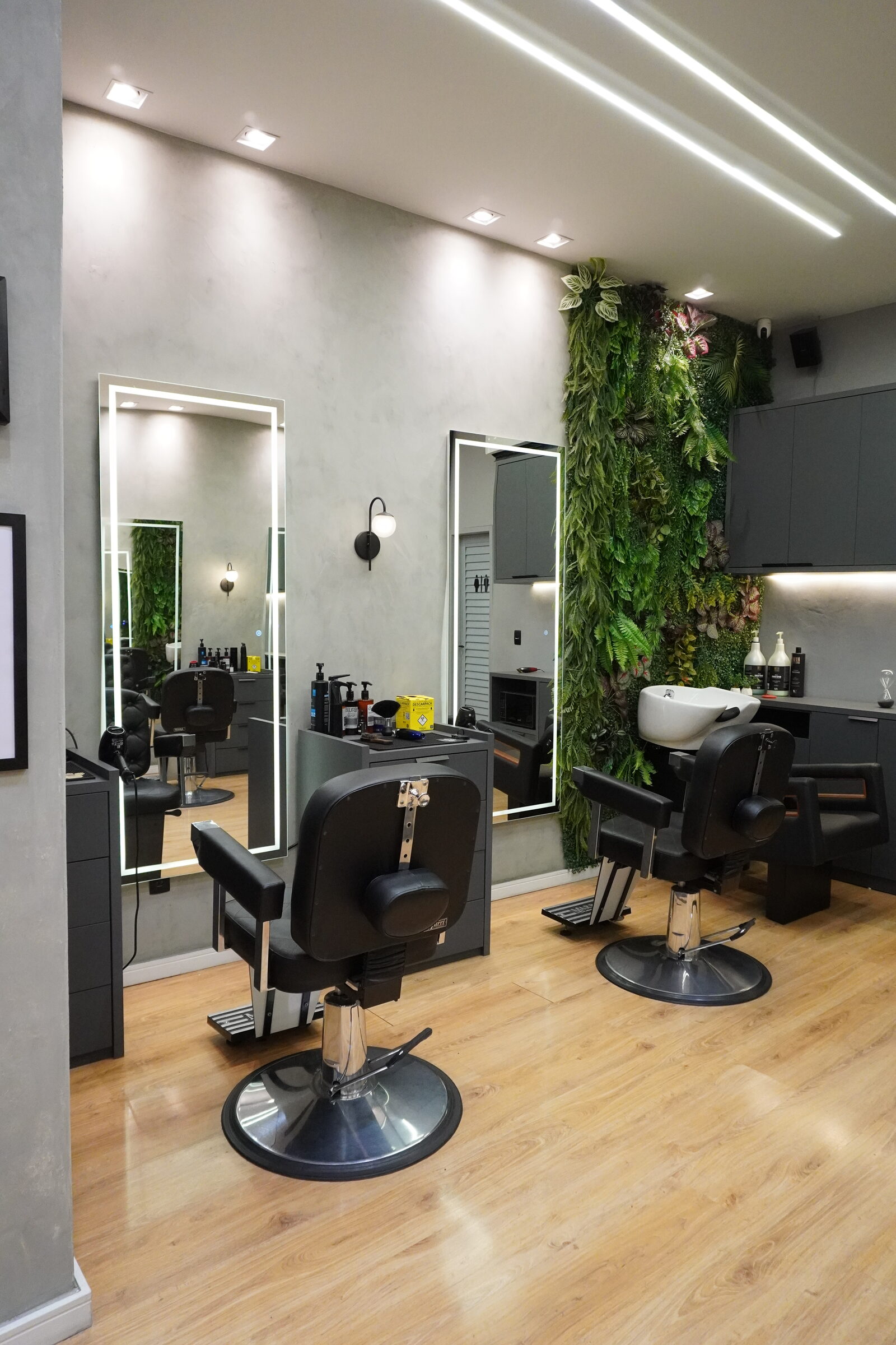 Interior climatizado da Iconic Barbearia com cadeiras e jardim vertical